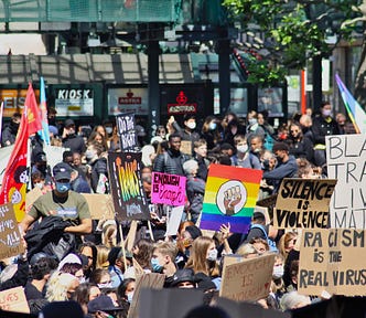 A photo of protestors with signs saying “Black trans lives matters” “silence is violence” and “racism is the real virus.”