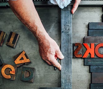 A hand lining up text on a letterpress machine