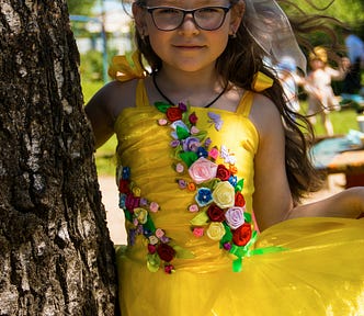 Young girl wearing black-rimmed glasses in bright yellow party dress