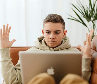 Young boy looking frustrated with what he has read on his laptop.