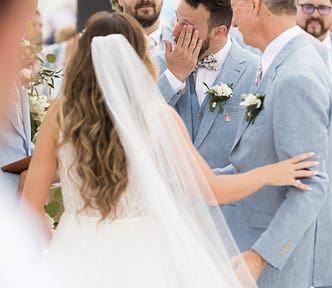 Groom wiping a tear at his wedding