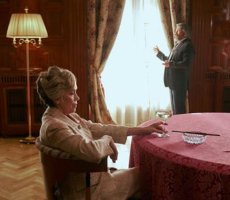 A wealthy older couple in a finely appointed great room.