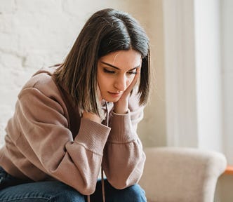 A girl sitting on a sofa looking worried.