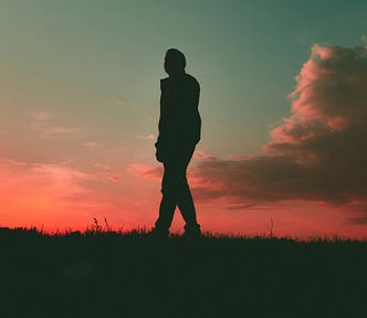 Silhouette of a man at sunset. Pink sky and clouds.