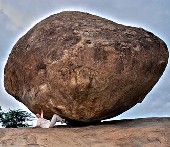 I’m lying on my back under a huge, round rock. I lean on the ground with one hand and touch the rock with the other hand and my two feet. I pretend I’m holding this ball of rock weighing thousands of tons. Meanwhile, I look at the camera with a comical smile.