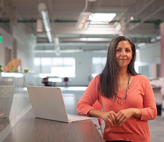 A lady smiling at the camera with a laptop by her side.