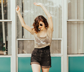 Young girl in sunglasses with arms raised as if to dance