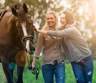 Two women hugging and petting a horse