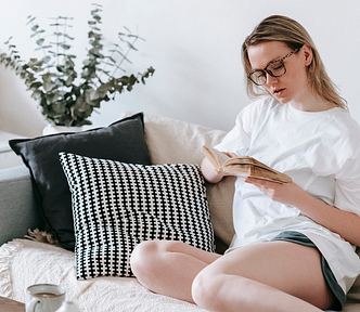 Focused woman reading book on sofa