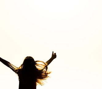 The back of a woman with her thumb up raising her arms in celebration