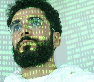 Close-up of a man with glasses and binary code projection.