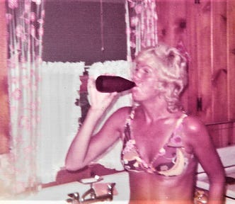 Authors mother drinking a beer in the kitchen at their beach cottage. She’s very tan, wearing a bikini. Circa 1974.