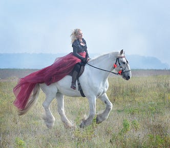 A woman riding a large white horse
