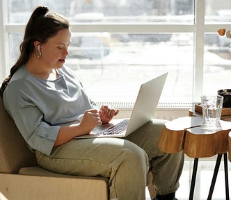 Woman sitting on a sofa while using a laptop.