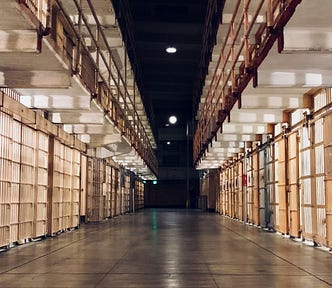 A long prison corridor with jail cells along each side
