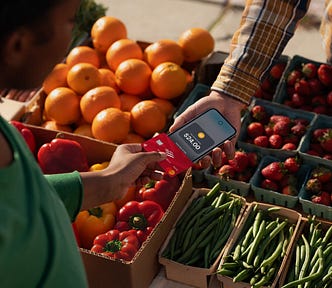 A customer uses Tay to Pay on iPhone to buy fruit at the farmer’s market.