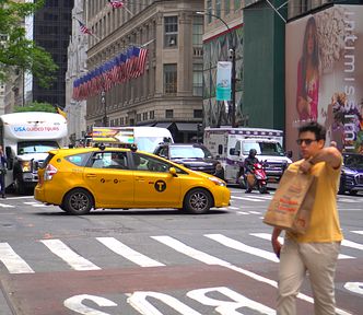 A congested New York City street with pedestrians and a yellow taxi.