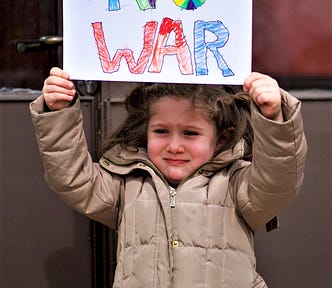 frightened young girl holding up sign reading “No War”