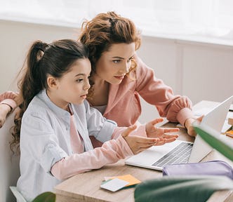 beautiful mother helping adorable daughter doing schoolwork at home