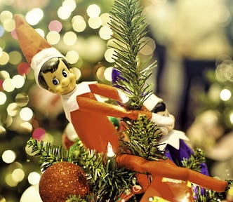 Elf on The Shelf close up holding onto Christmas tree