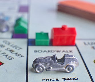 close up of a Monopoly board with a car on Boardwalk and houses and hotels around