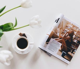 An open magazine next to a coffee cup