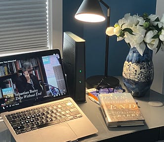 Sebastian Barry video plays on a laptop on a desk with a print copy of the book and a vase of flowers