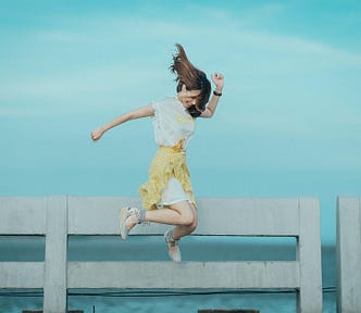 Woman jumping in front of fence along the shore