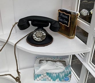 Antique rotary phone inside a Wind Phone, along with a box of tissues.