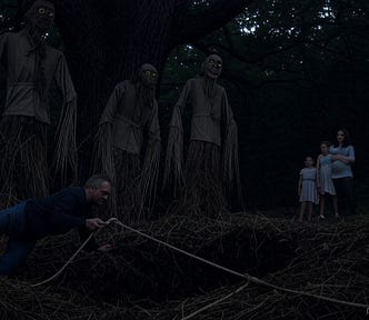 Seen in the fading light of dusk, three oversized scarecrows, seen more as shadowy apparitions with unnaturally long arms and legs, hollowed eyes of yellow straw, and pallid, grimacing expressions, skulk in the shadows of an oak tree forest at night. They look menacingly at a man descending into an opening in the forest floor. In the background, a pregnant mother embraces her two young daughters, all fraught with worry.