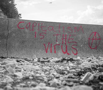 A grayscale image that shows a wall with red text graffitti. It says: Capitalism is the virus.