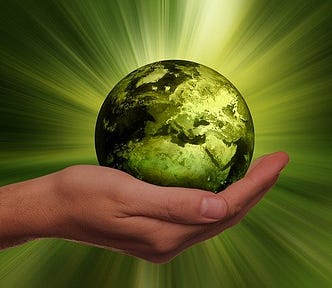 Green planet in palm of hand, radiating energy in all directions