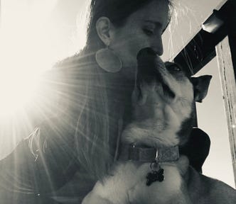 A black and white photo of the author and her dog, making awkward attempts at loving faces.