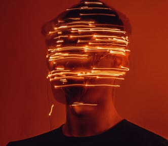 A man’s face is obscured with uneven streaks of light that wrap around his face. You can see the shadows of the different positions he was in, giving the image a confusing and disorienting effect.