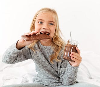 Pre-teen girl eating a whole bar of chocolate while holding a pot of chocolate spread. She’s having the time of her life.