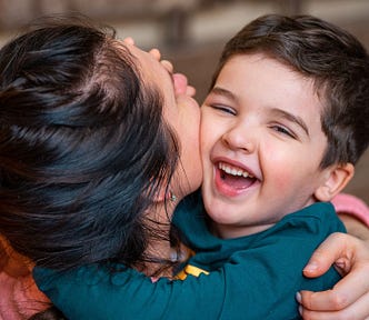 Young woman hugging a laughing child