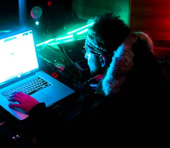 A man sitting at a desk looks at a bright computer screen.