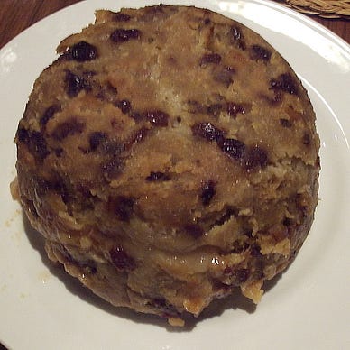 A spotted dick pudding on a white plate