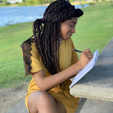 Woman sitting outdoors, writing.