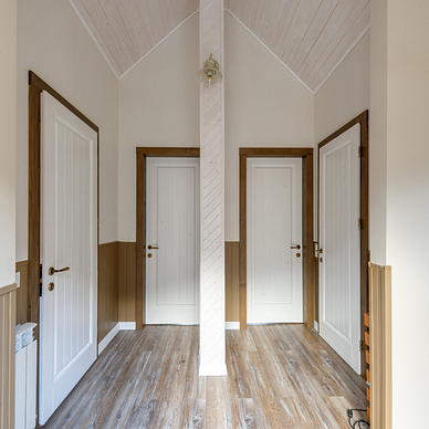 Within a two-toned hallway of white and brown, are four white doors. Two are across from each other. Two are directly next to each other.