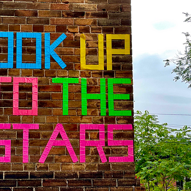 Brick wall with the words “Look up to the starts” written on it.