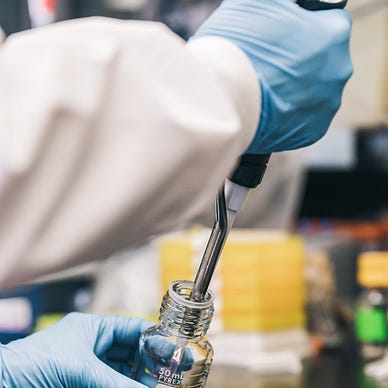 Scientist Injecting Red Liquid Into Bottle Photo