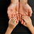 The hands of a child rest gently in the hands of an adult, against a dark wood background.