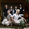 Conceptual photo of dancers clothed in white with people clothed in black behind them.
