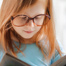 little girl reading a book. She wears glasses.