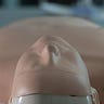 A CPR manikin lying face up on a grey floor