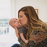 A photo of Chelsey Glasson holding and kissing her baby.