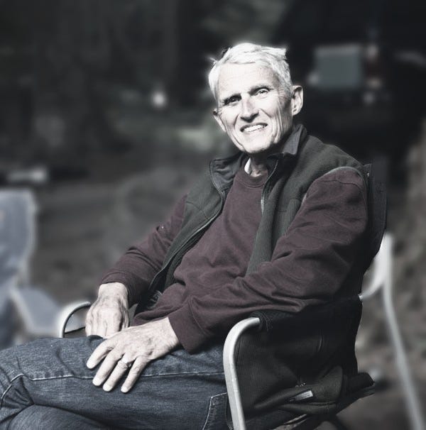 A smiling older man sitting in a camp chair