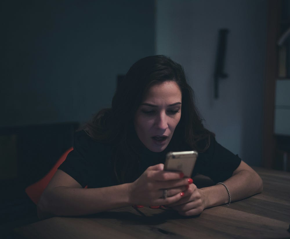 Woman staring at her phone and looking astonished.