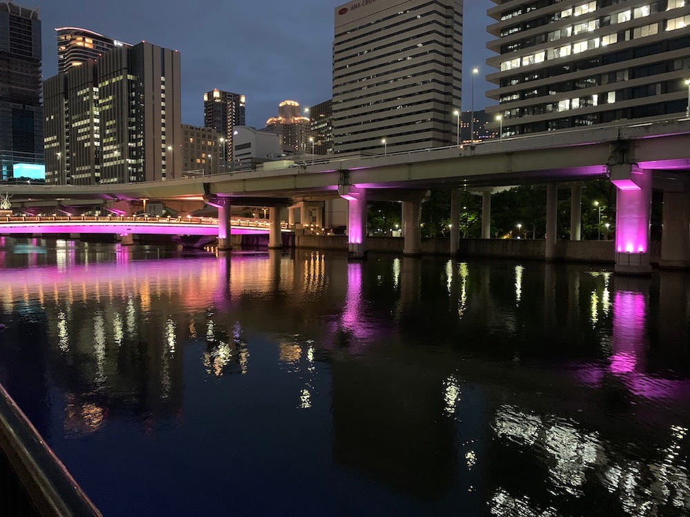 The Okawa river at night, lit from below — the surface of the water catching the light, the far bank quiet and dark, a breeze just barely visible in the reflections. (Photo by Takeshi Kitagawa)